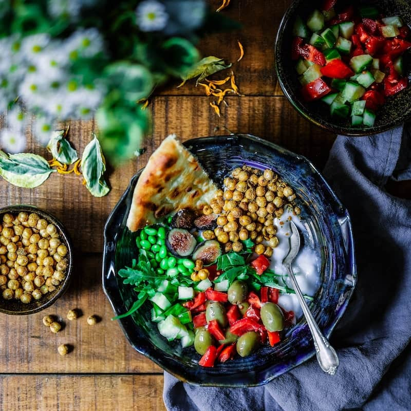 A wooden table filled with green vegetables and a dish in center